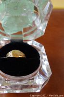 Close-up photo of the 10K gold ring in a clear faceted ring box with black velvet insert.