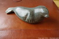 Top and side views of one dark stone seal sculpture showing the smooth body, facial features and flippers.