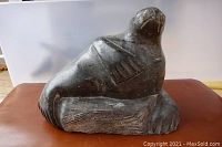 Front view of dark green soapstone seal sculpture on base