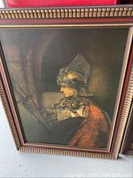 Full view of one framed art piece depicting a side-profile armored figure with a red cloak, showing frame and artwork details.