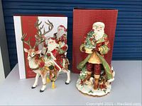 Two Fitz & Floyd Christmas Santa and reindeer figurines displayed with original boxes in background, showing detailed holiday decorations and motifs.
