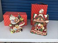 Two Fitz & Floyd ceramic Christmas cookie jars with original red and white branded boxes; Santa desk jar at left, theatre stage jar at right