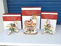 Three figurines displayed with Fitz and Floyd boxes behind on white surface