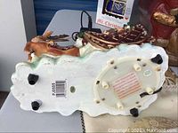 Bottom view of a Christmas themed figurine, shows base with electrical components and feet