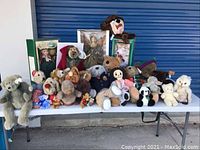 Wide shot of all dolls and bears on a table including boxed items and loose plush toys