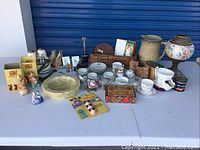 Full spread of assorted decorative items on table including ceramics, figurines and boxes