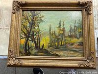 Full view of framed oil painting showing landscape with trees and path, includes wear on frame and visible painting texture.