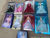 Nine Barbie dolls in original boxed packaging arranged outside, showing clear-front boxes with dolls in detailed fashion attire.