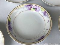 Close-up of one porcelain bowl showing purple floral design and gold rim