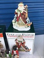Large Fitz & Floyd musical Santa decorative figurine displayed on its original box, finely detailed with winter clothing and forest animals.