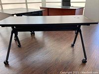 Photo of the rolling office desk showing overall top surface and legs with casters, highlighting furniture condition and design.