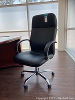 Front view of black rolling office chair with cushioned seat and backrest, plastic armrests, on chrome base with caster wheels.