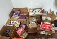 Multiple cardboard boxes filled with assorted teaching materials, workbooks, arts and crafts supplies, games, and other teaching items.
