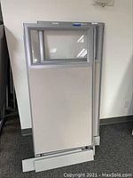 Single cubicle panel showing gray lower panel with glass upper section and base support on floor against a wall