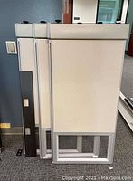 Three stacked beige fabric covered office cubicle panels each with top glass windows and aluminum frames