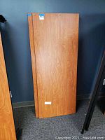 Full view of the woodgrain laminate desktop panel for cubical setup, showing rectangular shape and attached hangers.