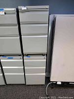 Front view of beige metal file cabinet with three drawers and lock on top drawer