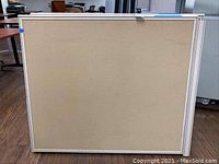 Front view of a beige fabric-covered office cubicle partition with metal frame.