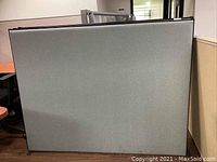 Photo showing front of fabric and metal framed cubicle partition panel in light gray fabric.