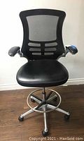 Front view of the adjustable office chair showing padded black seat, black mesh backrest with lumbar support, armrests with blue accents, and silver base with casters and footrest.