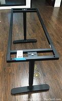 Black metal IKEA table frame with two legs shown from above on wooden floor, highlighting rectangular frame and leg bases