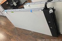 Photo of two grey office cubicle partitions leaning on floor, showing smooth grey panel surface and metal rail attachments on top edges with black hardware.