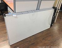 Two grey office cubicle partitions laid flat with metal edges and mounting rails visible