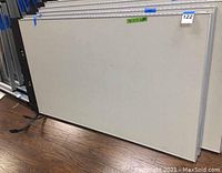 Photo of a light-colored rectangular cubicle partition panel standing on floor showing one full panel.