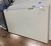 Two large rectangular office cubicle panels stacked upright, showing light grey surface with metal edging on the floor.