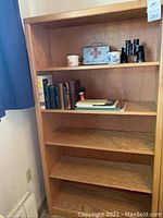 Full view of wooden bookshelf with items on top two shelves and three empty shelves below