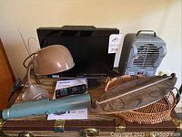 Full lot arrangement showing TV, lamp, telescope, paddle, baskets and heater on top of chest