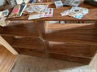 Photo of two wooden bookshelves with open shelves and various stamps and old papers on top.