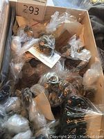 Box with multiple small plastic bags containing assorted vintage metal buttons with different designs and patterns.