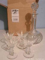 Photo showing the full set of 1 decanter with stopper and 4 crystal glasses together on a table with the box in background