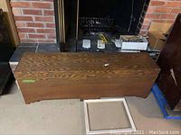 Large wooden tool chest laid horizontally on the floor with visible wood grain and some scratches.