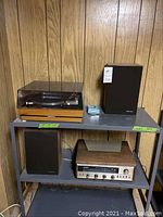 Photo showing the United Audio record player with dust cover on top left and two Realistic speakers on the right and bottom shelf, with the Realistic stereo master receiver below record player