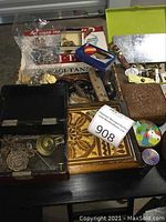 Overview of multiple decorative boxes, military medals, arrowheads and candle holder arranged on tabletop