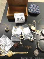 Overall lot display with wooden box and various jewelry pieces including necklaces, earrings, brooch, watch and bracelets
