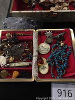 Overhead view of jewelry box compartment showing assorted necklaces, carved pendants and turquoise beads.