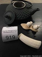 Black cast iron teapot, metal strainer, two porcelain birds on base, bone tusk