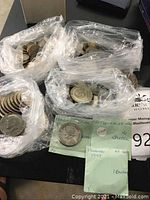 Three plastic bags of mixed coins and two green envelopes showing labeled Panama Balboa samples.