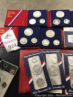 Five red US Bicentennial proof sets and five blue US Bicentennial silver uncirculated sets in original folders, plus a Republic of Panama proof set visible in tray.