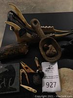 Overall view of lot on black table: comb, spoon, toggles, tile and disk visible