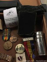 Overview photo showing medals, coins, black knitted booties, and metal cup