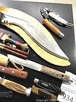 Overview of lot showing large curved blade, multi-tools, fixed blades and assorted handles