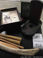 Overview of framed print, metal snap trap, wooden rods, and driftwood piece