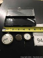 Photo of two vintage Elgin pocket watches with measuring tape showing size, one larger watch and one smaller watch with cover closed, viewer can note size and condition.