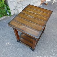 Angled top-down view showing the scuffed wooden top surface and the lower wooden shelf, with the metal accents on corners partially visible.