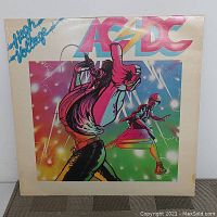 Front cover of AC/DC High Voltage vinyl record showing colorful artwork with band members and AC/DC logo.