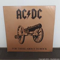 Front cover of AC/DC For Those About to Rock vinyl album showing cannon illustration and band name.